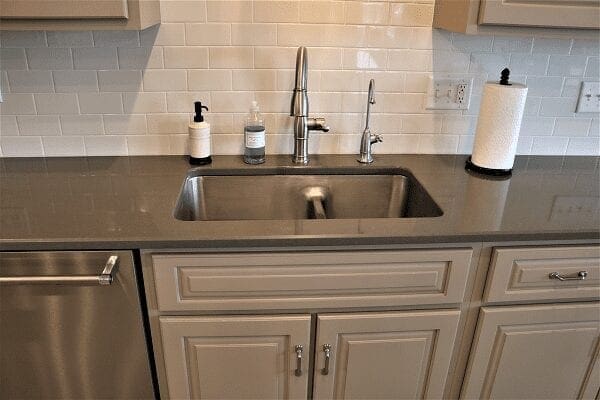 kitchen sink and cabinets with tiled wall